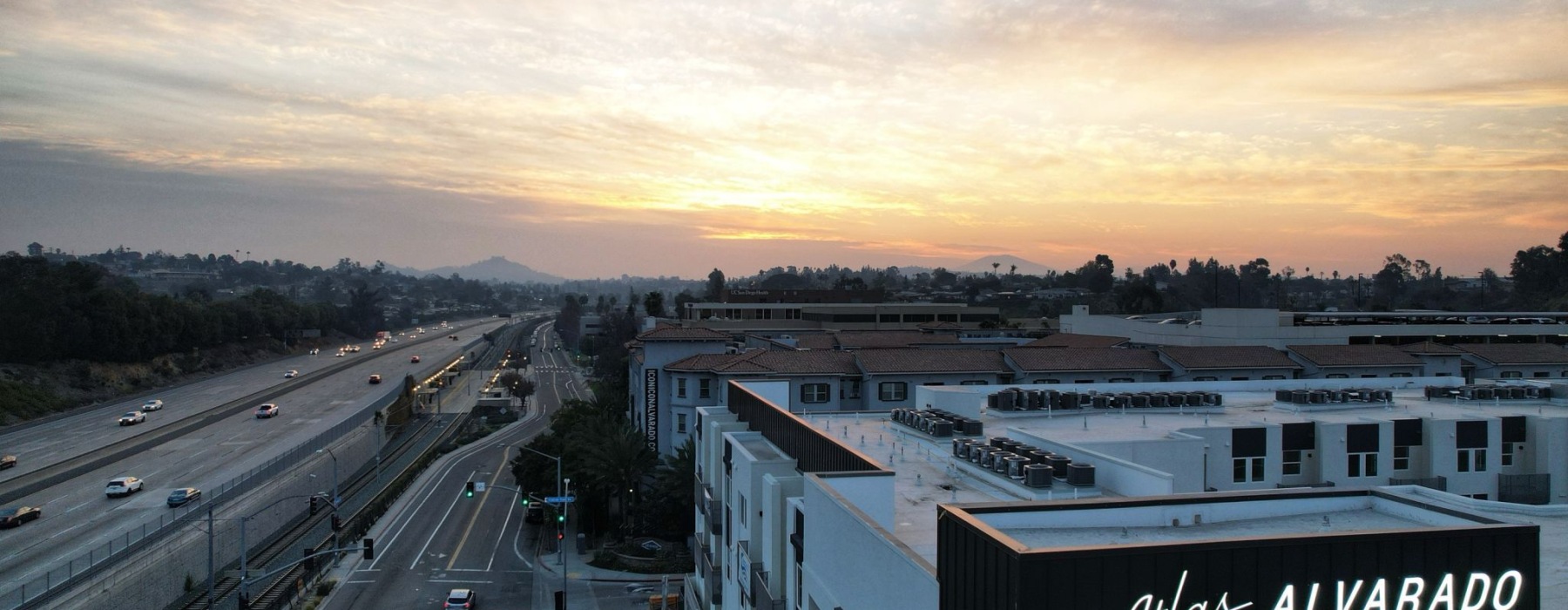 Sky shot of Atlas Alvarado building sinage with highway to the left of building during sunrise