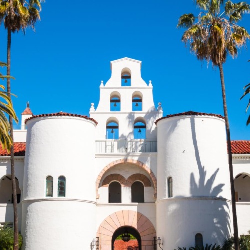 a white building with palm trees with San Diego State University in the background